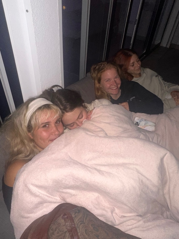 Freundinnen kuscheln sich abends zusammen unter eine Decke