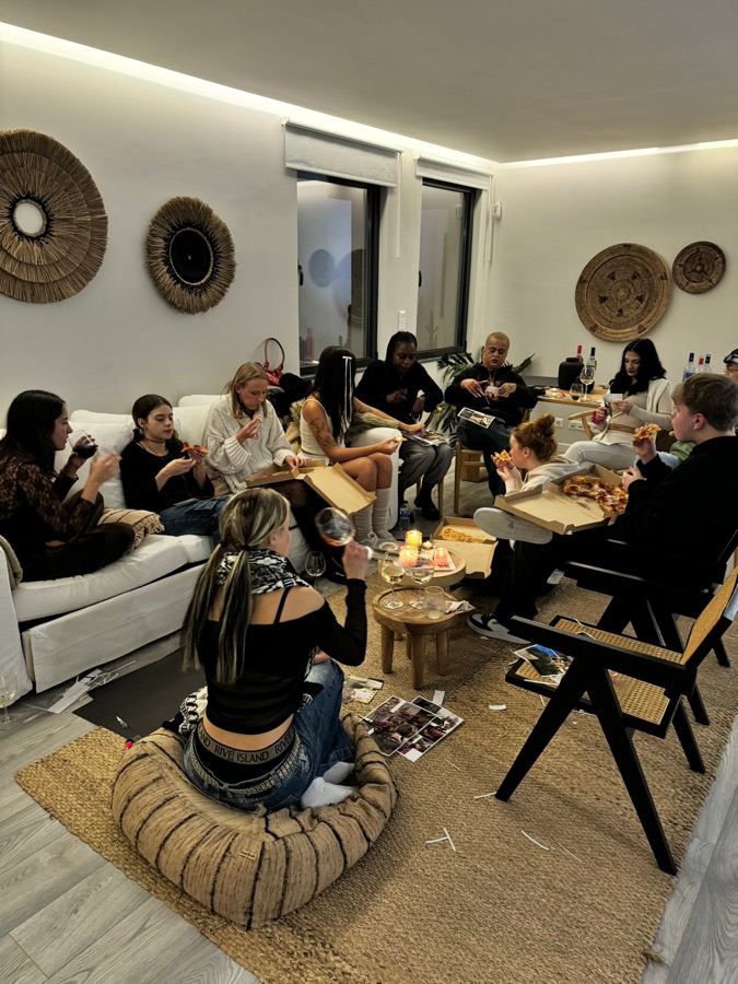 Die Gruppe sitzt abends im Wohnzimmer der Villa zusammen