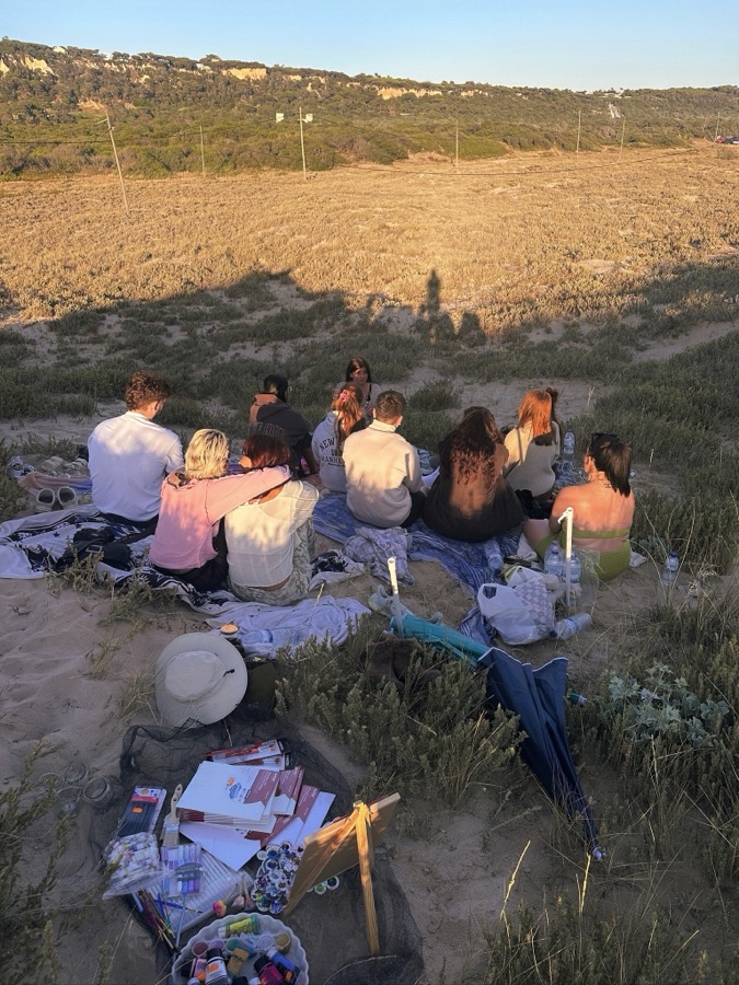 Gruppe sitzt auf Decken an den Klippen